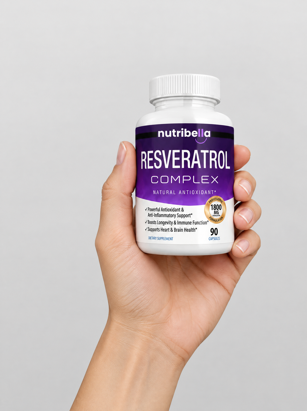 A hand holding a bottle of Nutribella Resveratrol Complex 1800mg